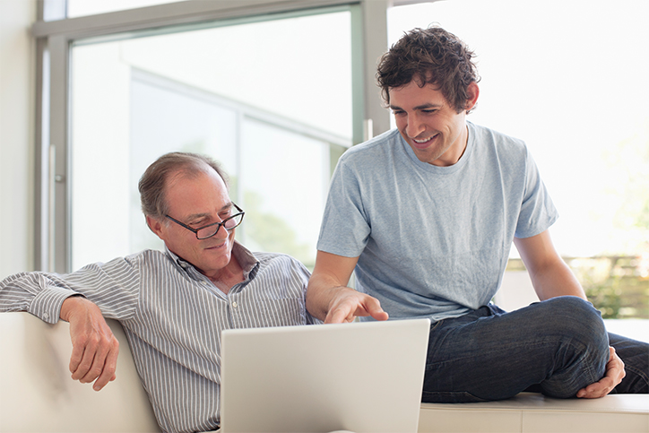 elderly father with adult son looking at laptop