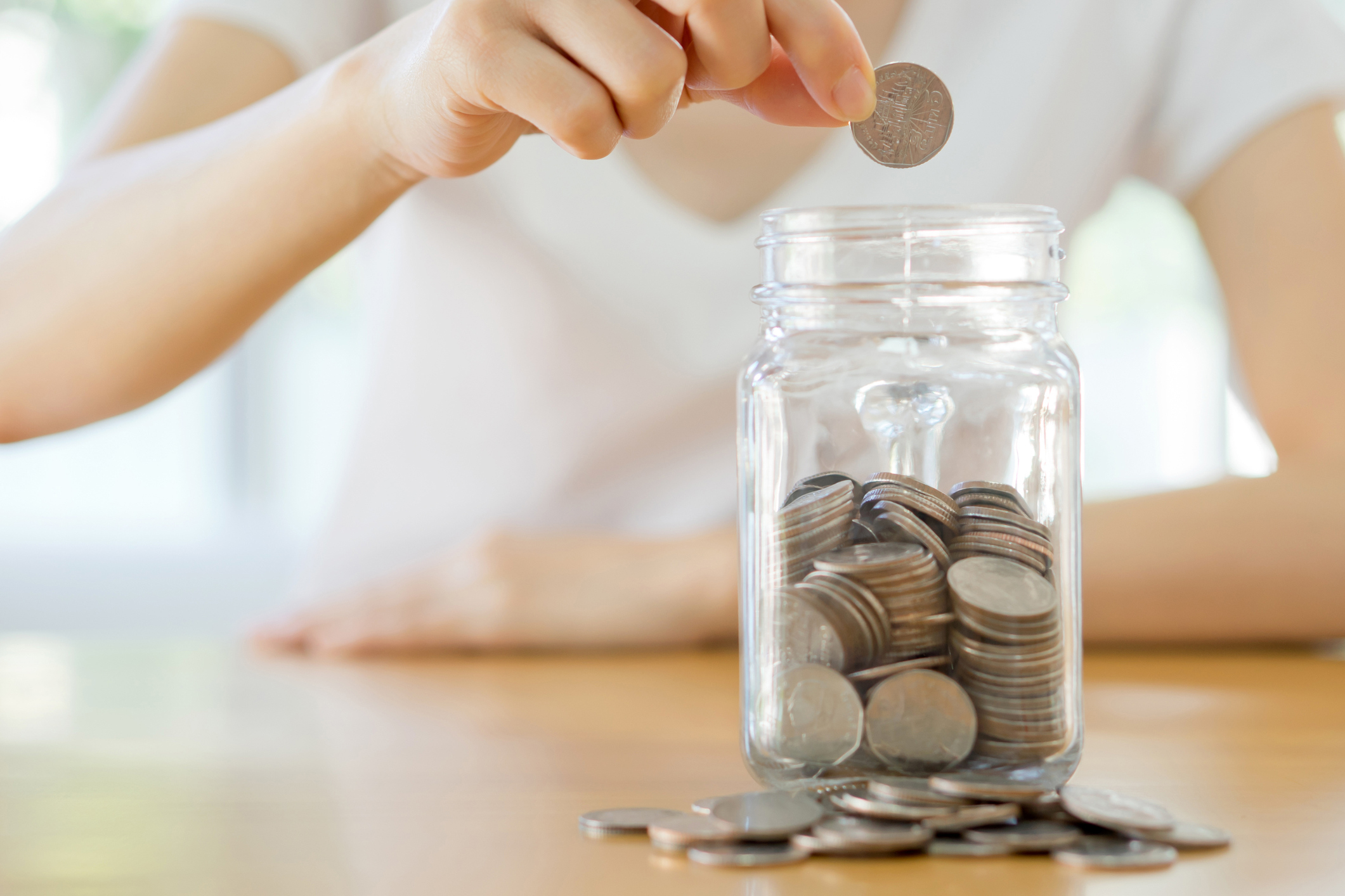 woman dropping coins into a glass jar