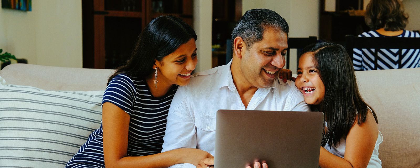 family sitting together in front of a laptop