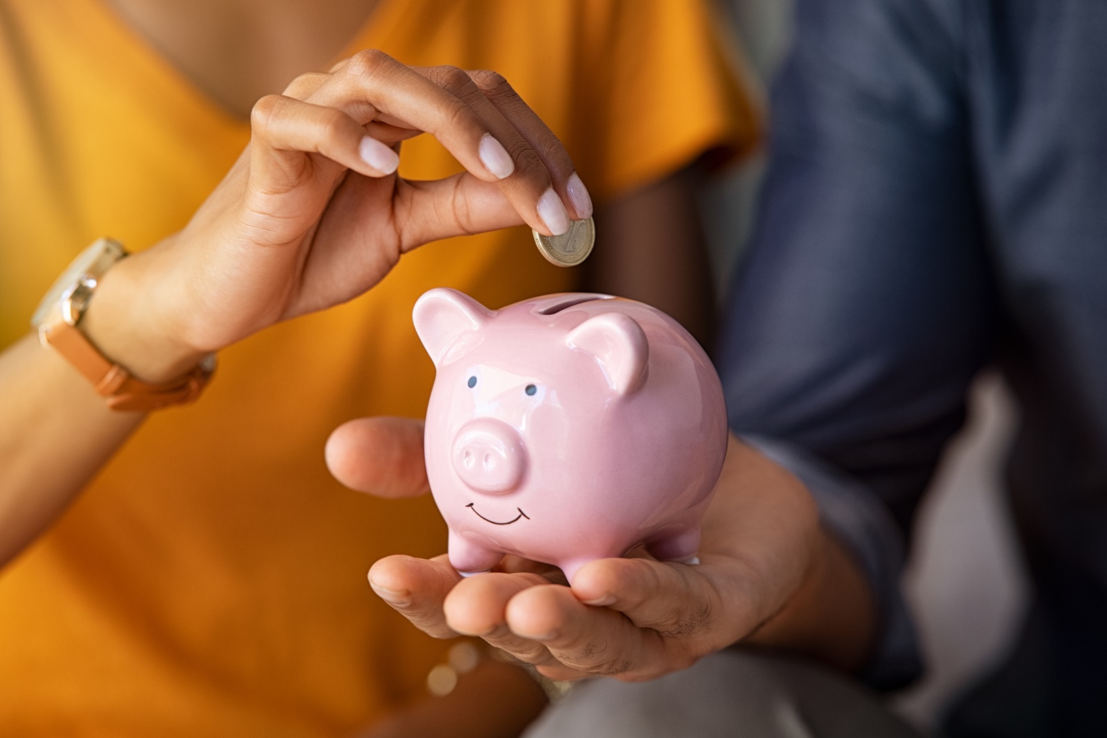 People putting coins in piggy bank