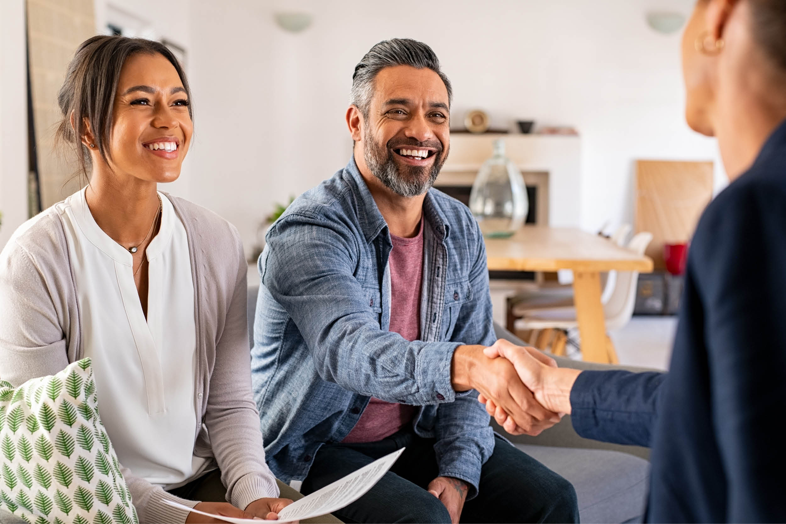 couple smilaing with man hand shaking another person